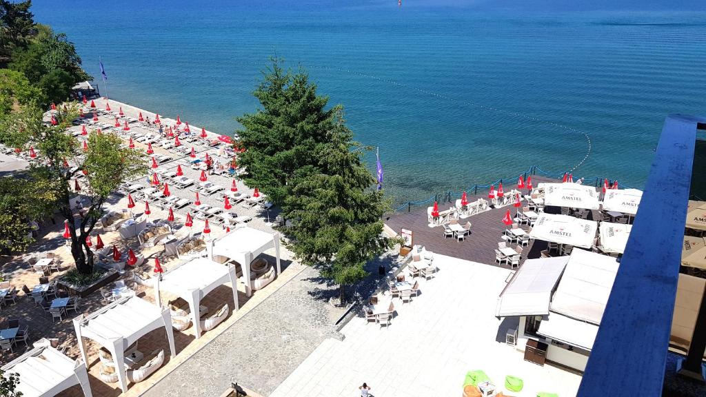 einen Blick über den Strand mit Stühlen und Sonnenschirmen in der Unterkunft Park Ej's Lake and Pool View A89 in Ohrid
