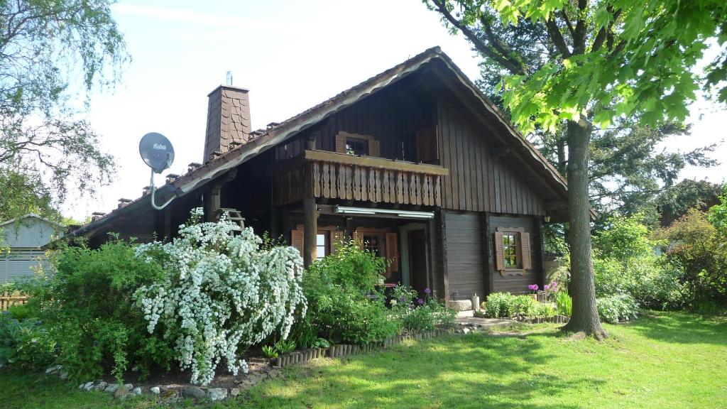 ein kleines Holzhaus mit einem Baum und einigen Büschen in der Unterkunft Ferienhaus Zur Einberger Schweiz in Rödental