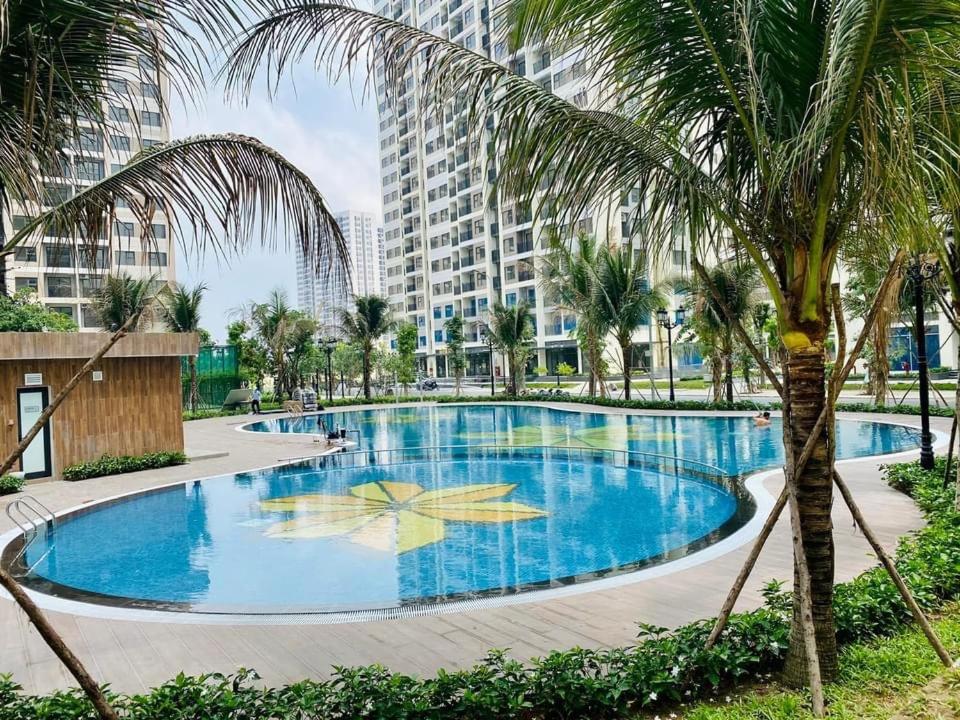 a large swimming pool with a palm tree and a building at Mayhomes 34m2 Vinhomes Grand Park in Long Bình