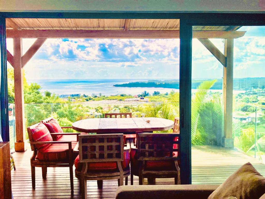 a patio with a table and chairs and a large window at Villa Teranga avec vue panoramique sur la baie de Tamarin in Tamarin
