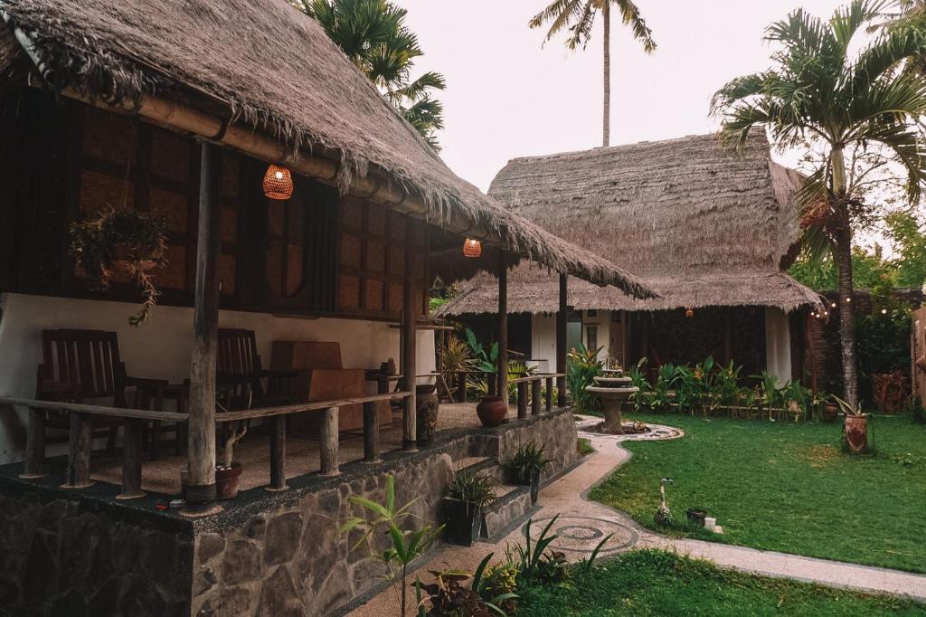 una casa con techo de paja y patio en Sasak Experience, en Kuta Lombok