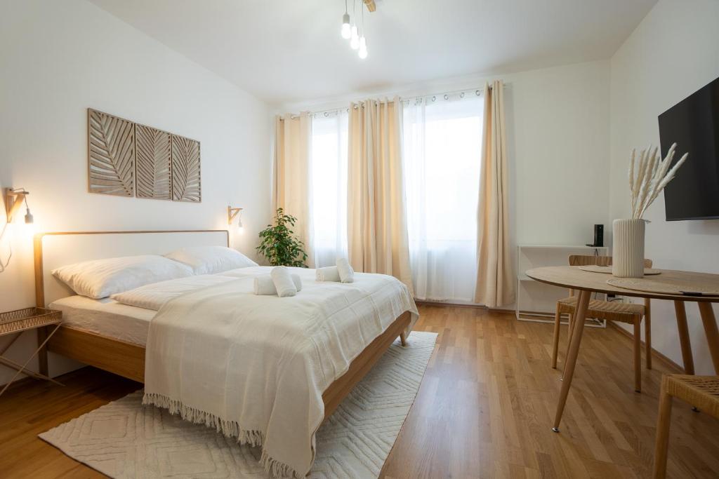 ein weißes Schlafzimmer mit einem großen Bett und einem Tisch in der Unterkunft Bright and cozy studio with a city view in Wien