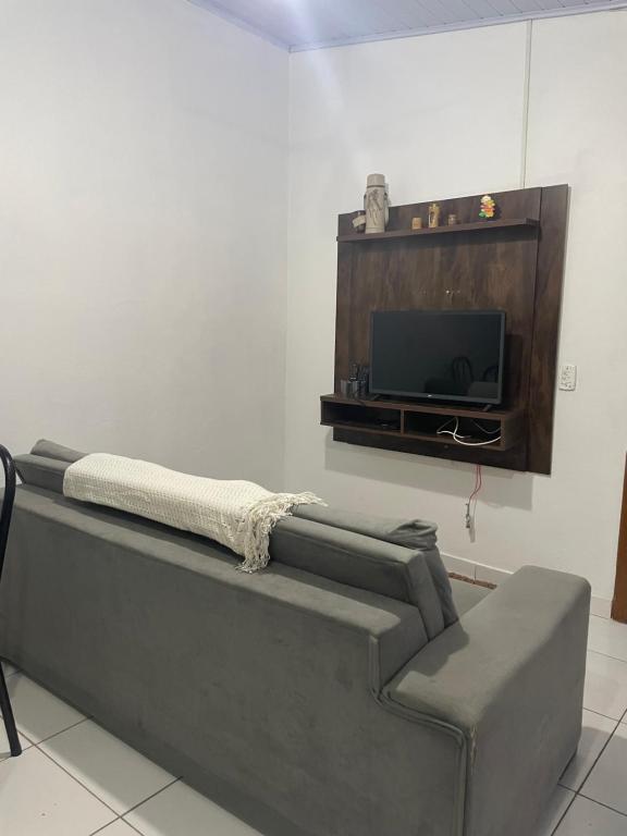 ein Wohnzimmer mit einem Sofa und einem TV in der Unterkunft Casa 01,02 in Bombinhas