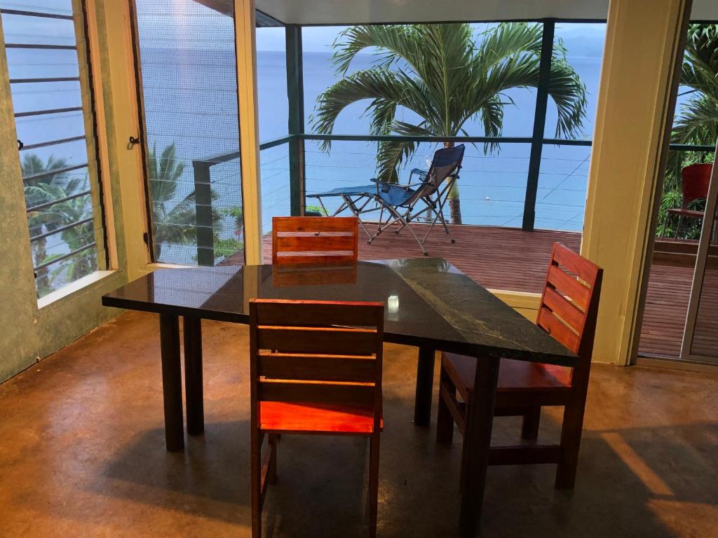 a dining room table with chairs and a view of the ocean at Limericks by the Sea in Savusavu