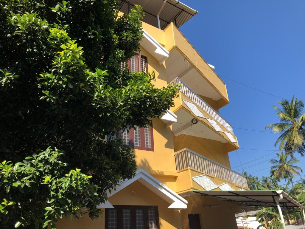 Un edificio amarillo con árboles delante. en Angel Valley, en Trichūr
