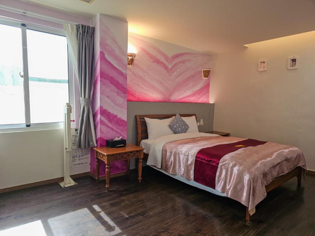 a bedroom with a bed with a pink wall at Kenting Garden Homestay in Kenting