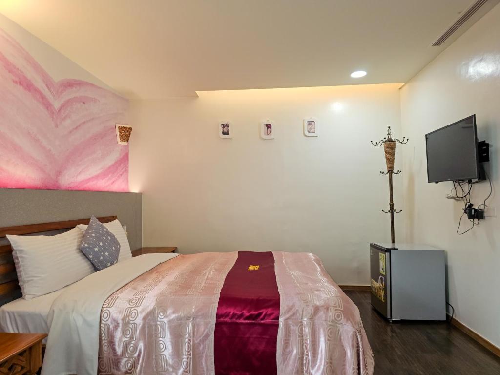 a bedroom with a bed and a flat screen tv at Kenting Garden Homestay in Kenting
