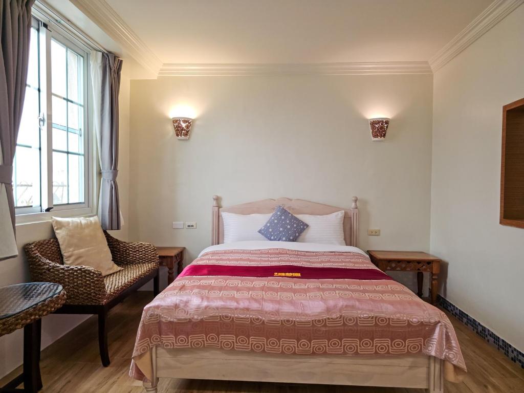 a bedroom with a large bed and a chair at Kenting Garden Homestay in Kenting