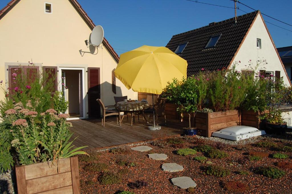 a backyard with a wooden deck with a yellow umbrella at Terrassenwohnung in Neustadt an der Weinstraße