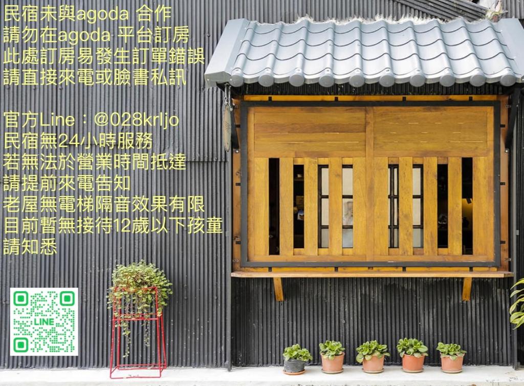 un bâtiment avec une porte en bois et des plantes en pot dans l'établissement Xin Yuan Hang Homestay, à Guanshan