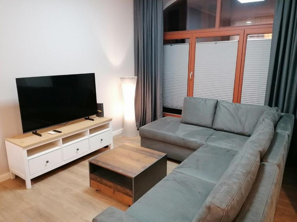 een woonkamer met een bank en een flatscreen-tv bij Cityflair Nähe Marktplatz - ABC328 in Wismar