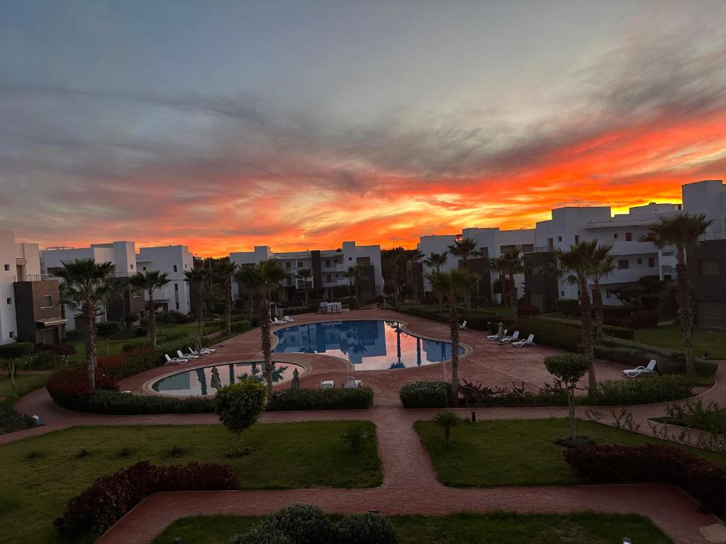 um pôr-do-sol sobre um resort com piscina e palmeiras em MSVIP PERLA SAIDIA GH1 s em Saidia 