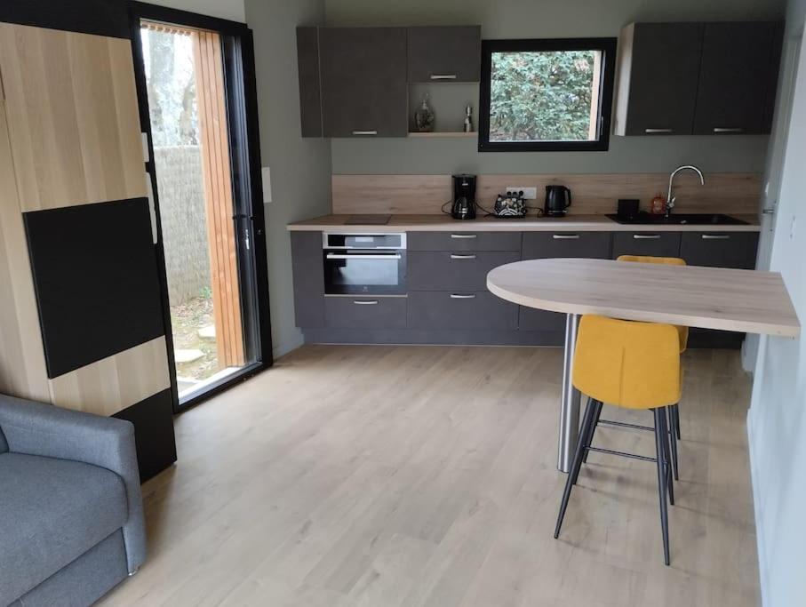 a kitchen with a table and two yellow chairs at Studio tout neuf proche Rennes in Saint-Grégoire