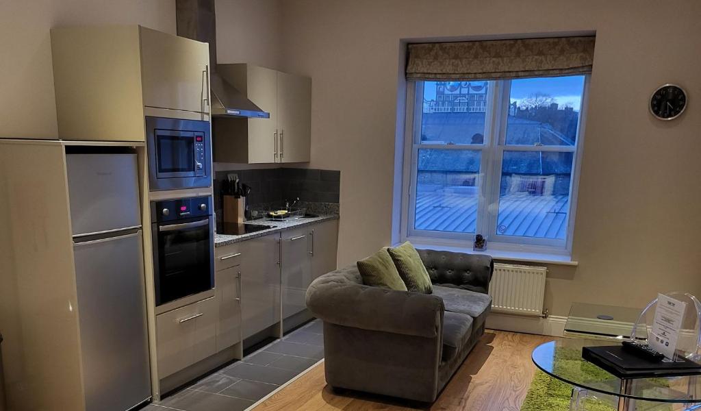a living room with a chair and a kitchen at Harrogate Lifestyle Luxury Serviced ApartHotel in Harrogate