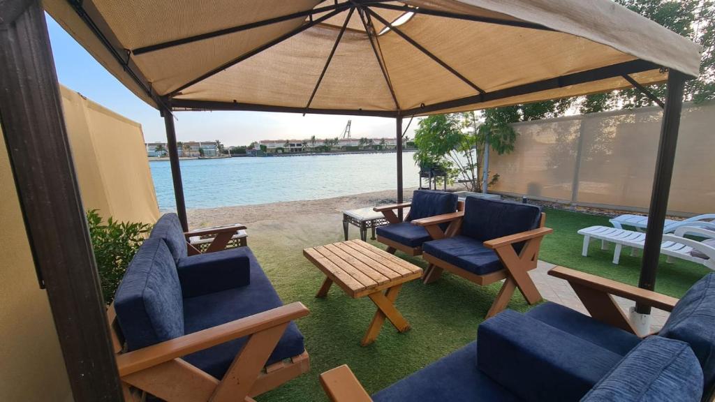 eine Terrasse mit Stühlen, einem Tisch und einem Sonnenschirm in der Unterkunft فيلا على البحر بمسبح خاص وشاطى رملي in Durrat Al-Arus
