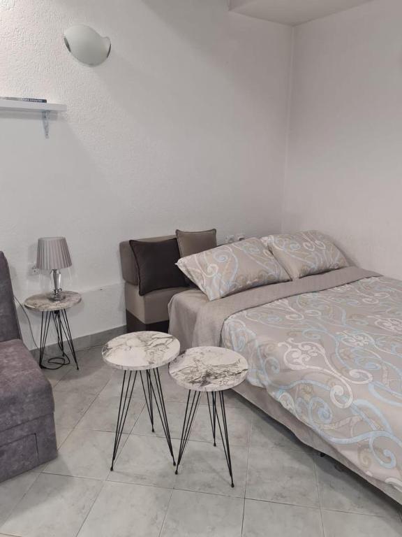 un soggiorno con un letto e due tavoli di Apartman Sofija Kraljevo a Kraljevo