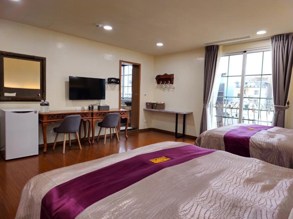 a hotel room with two beds and a desk and a television at Kenting Garden Homestay in Kenting