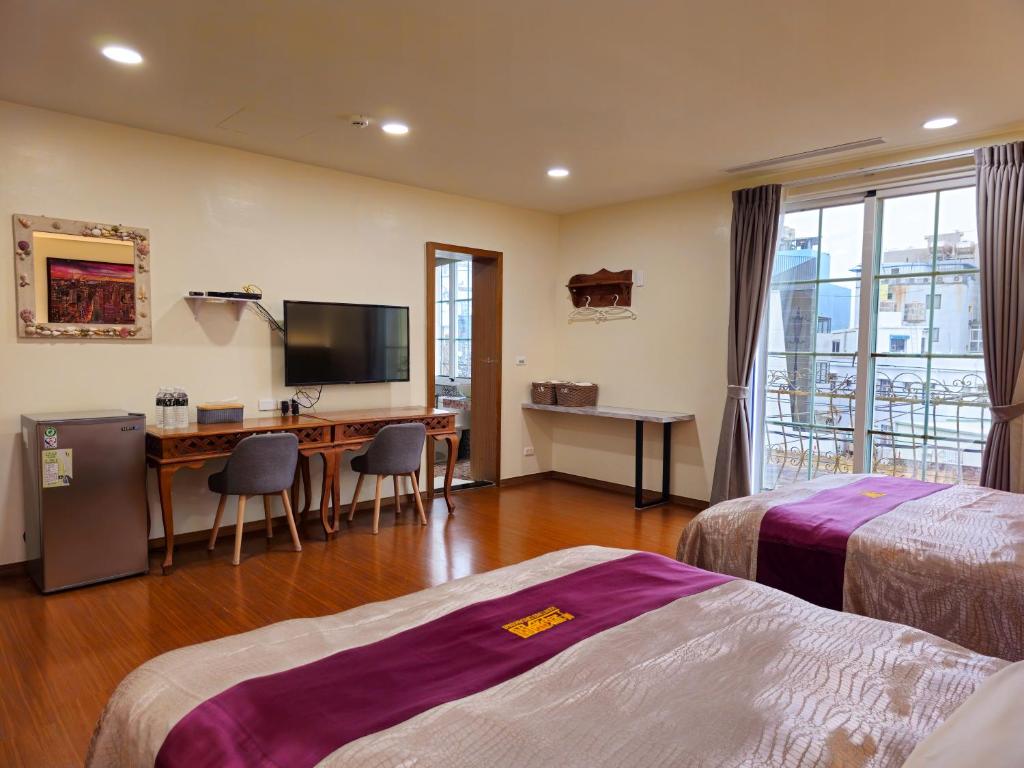 a hotel room with two beds and a desk and a television at Kenting Garden Homestay in Kenting