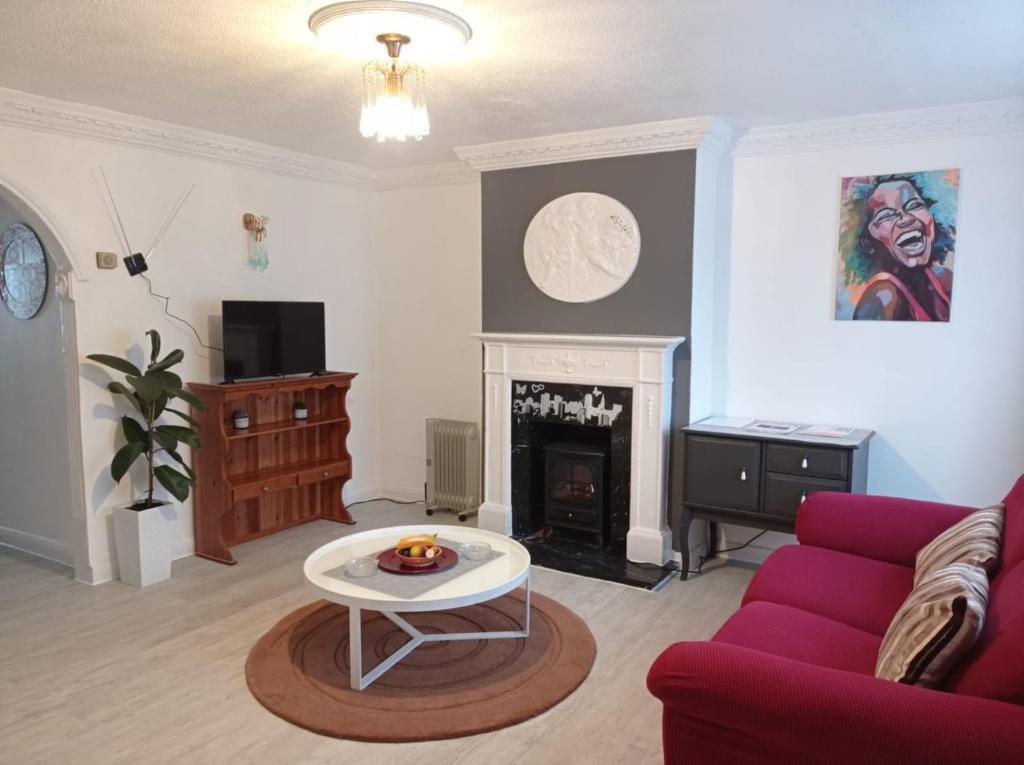 a living room with a red couch and a table at Shepherds Spacious House 4-Beds in Romford