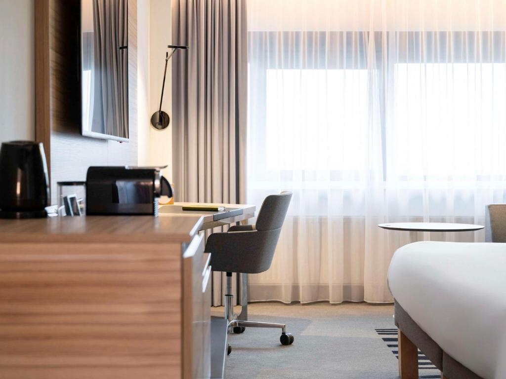 a hotel room with a bed and a desk with a chair at Novotel Amsterdam City in Amsterdam