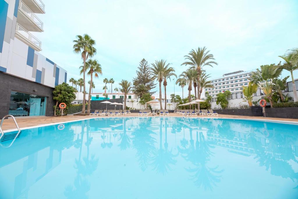 a large swimming pool with palm trees and a building at Labranda Marieta & Spa - Adults Only in Playa del Ingles