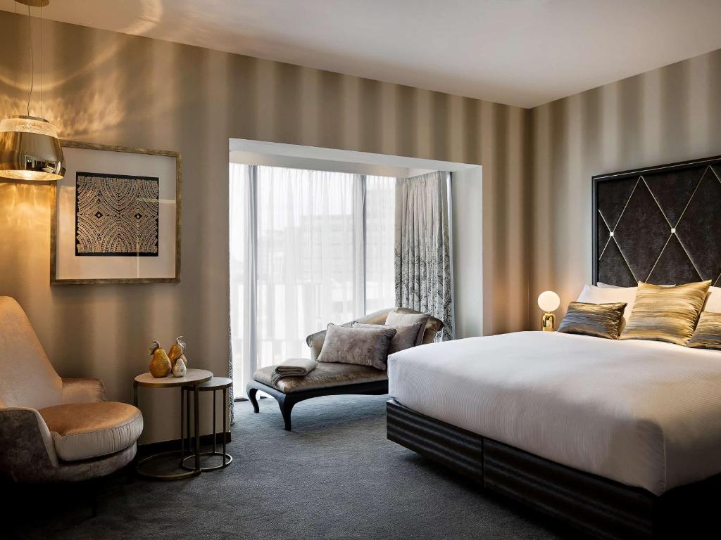 um quarto com uma cama, uma cadeira e uma janela em Sofitel Wellington em Wellington