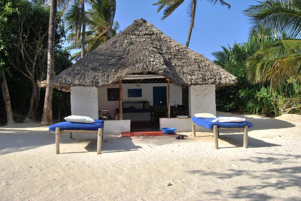 uma pequena cabana com duas cadeiras na praia em Beach Bungalow 60sqm Fully serviced in Matemwe Zanzibar em Gazija