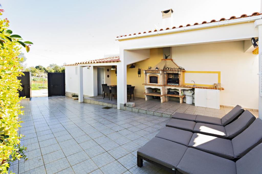 a patio with black chairs and a house at Casa Correia - Charming Holidays House in Vila Nova De Cacela