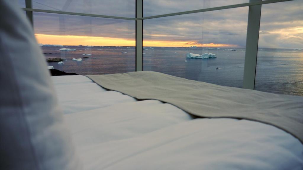 a bed in a room with a view of the ocean at Hotel Arctic in Ilulissat