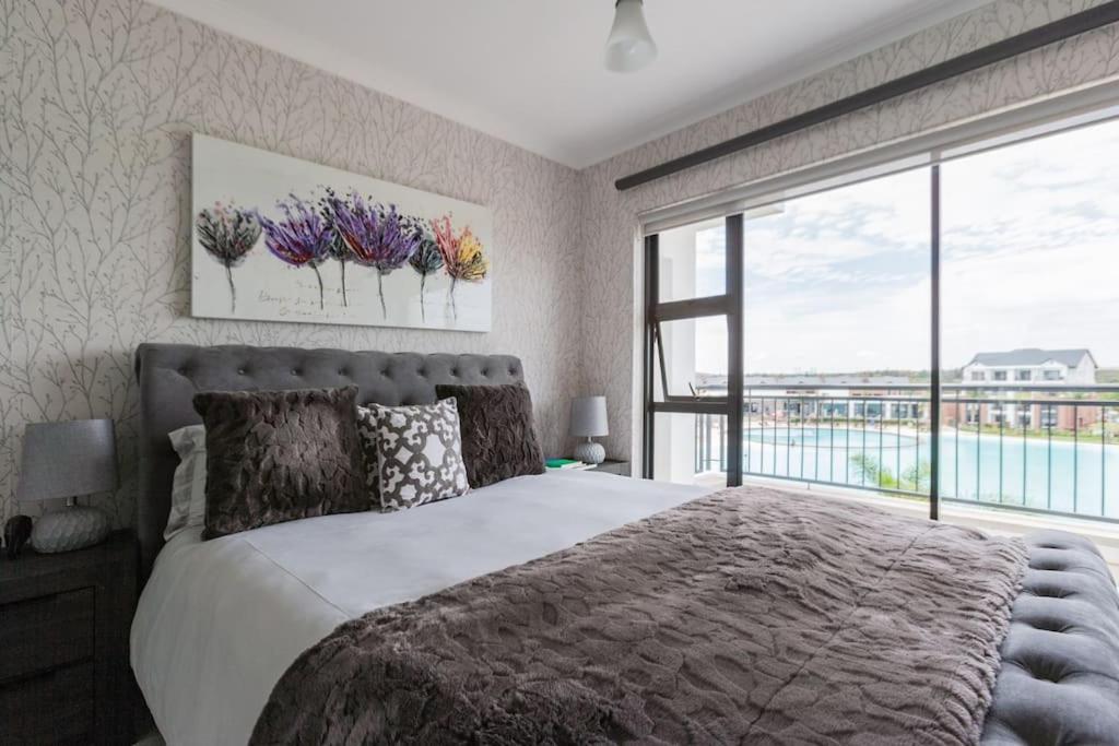 a bedroom with a large bed and a large window at Pax's Luxury Romantic Penthouse on the Lagoon in Pretoria