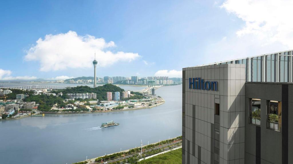 Hilton Zhuhai في تشوهاى: مبنى بجانب نهر فيه قارب