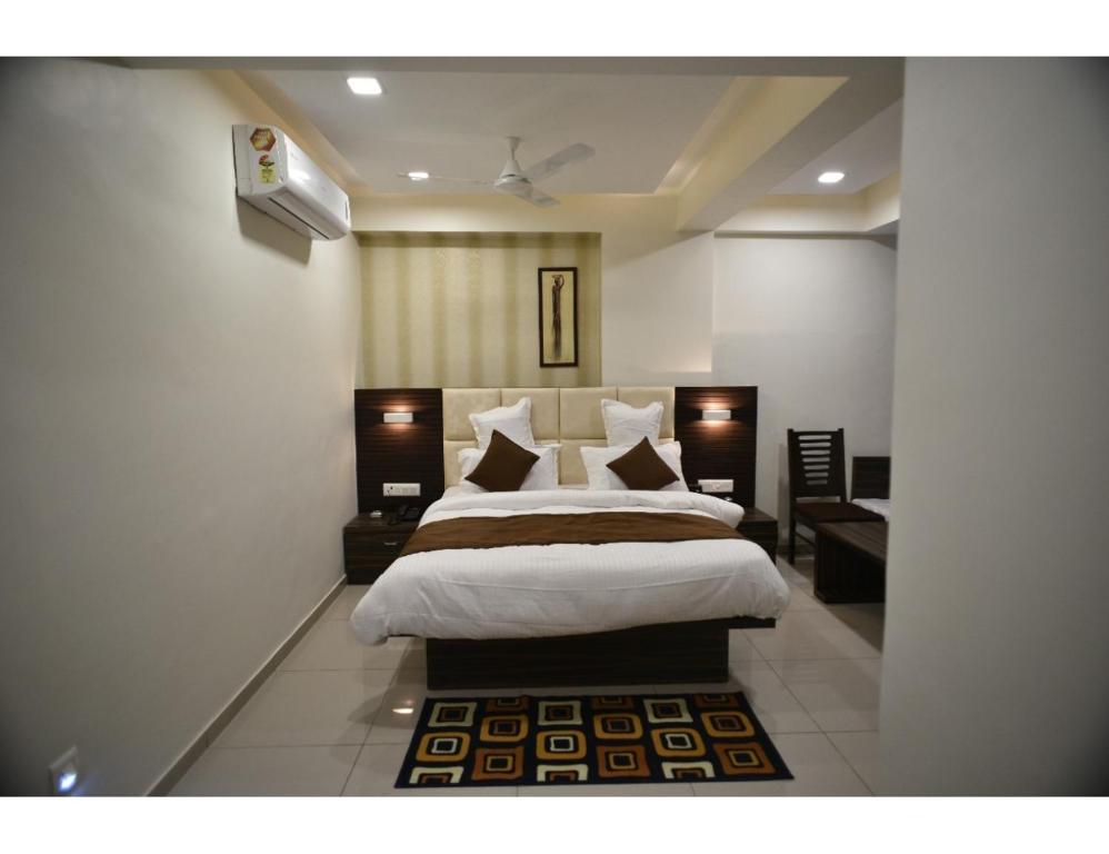 een slaapkamer met een groot bed met witte lakens en kussens bij Hotel Royal Residency, Vadodara in Vadodara