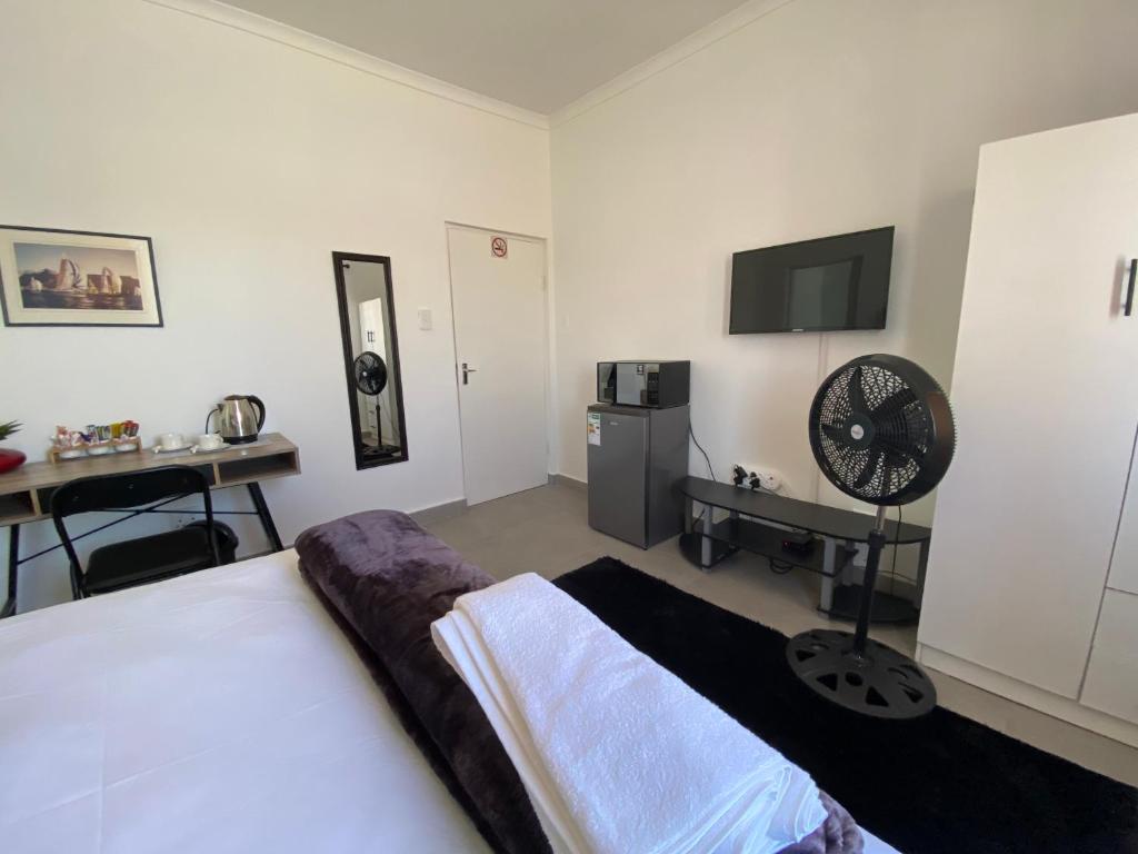 a bedroom with a bed and a desk with a fan at No 1 Guest house in Cape Town