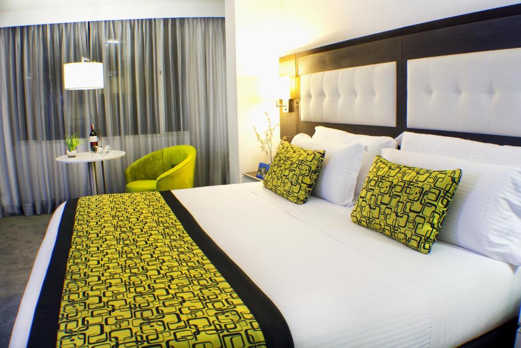 una habitación de hotel con una cama grande con almohadas amarillas en Hotel City Bog Expo Museo, en Bogotá