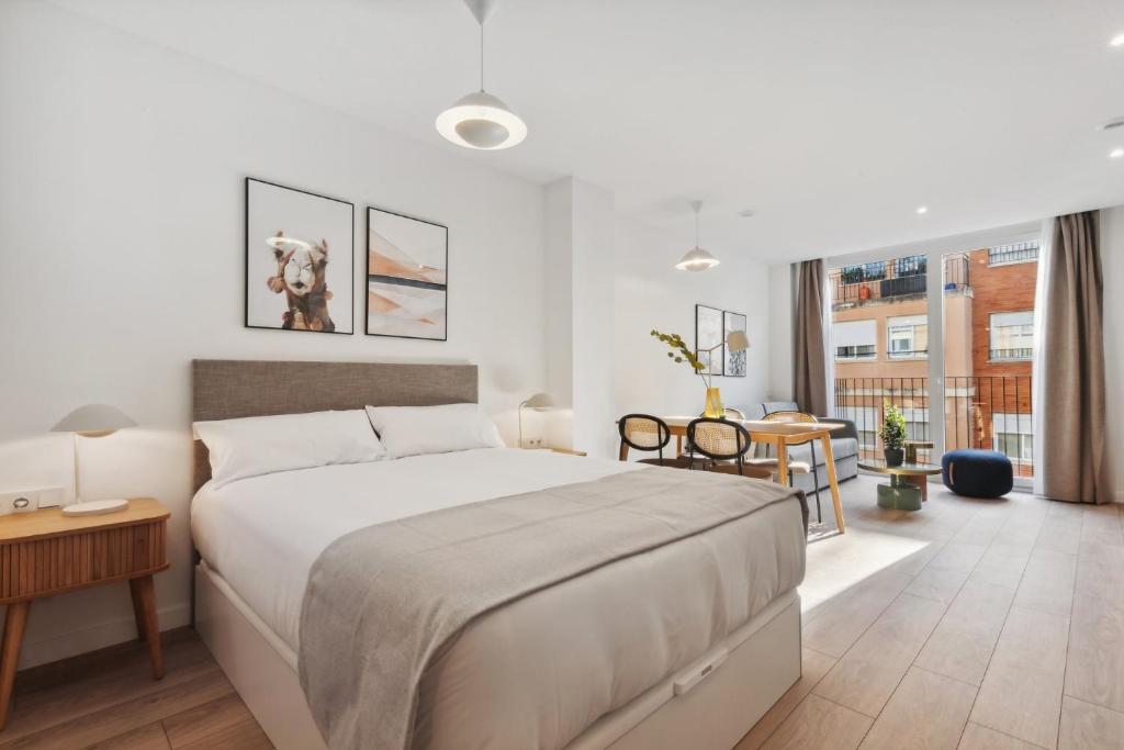 um quarto com uma grande cama branca e uma mesa em limehome Valencia Carrer del Pare Palau i Quer em Valência