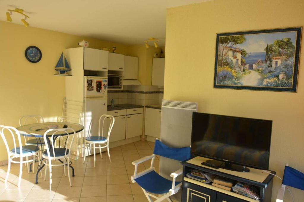 cocina y comedor con mesa y TV en AS24091- P3 Dans un secteur calme avec parking privé, en Le Grau-du-Roi