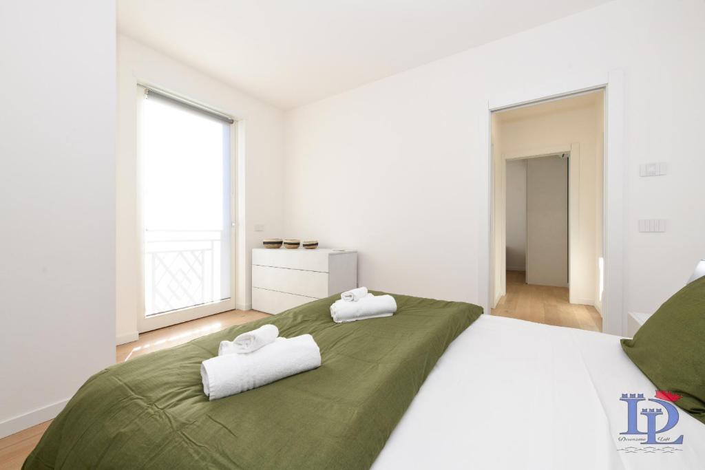 1 dormitorio con 1 cama grande y 2 toallas. en DesenzanoLoft Smeraldo Family apartment en Desenzano del Garda