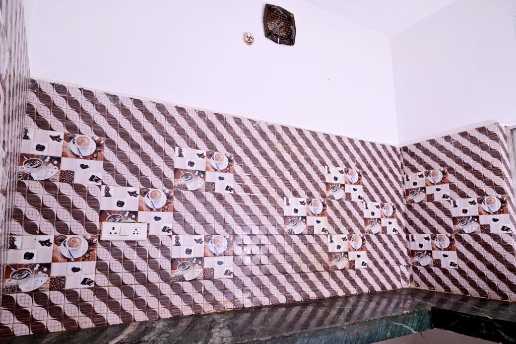 a tiled wall with pictures on it at Shivay Guest house in Jasidih