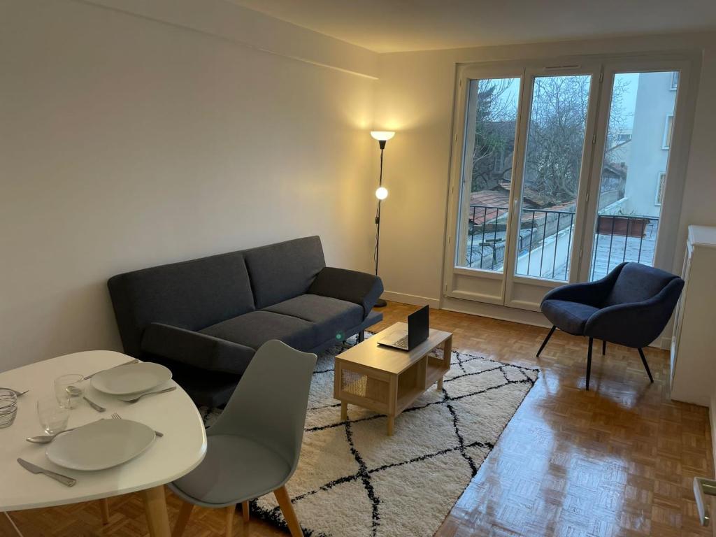 uma sala de estar com um sofá, uma mesa e cadeiras em 5 people/Paris-CDG/France Stadium em Bagnolet