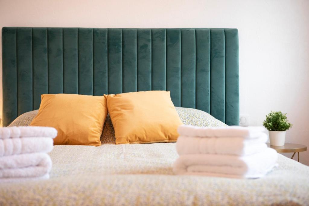 a bed with yellow pillows and a green headboard at # La Roselière # Parking gratuit # Calme # proche Mulhouse in Riedisheim