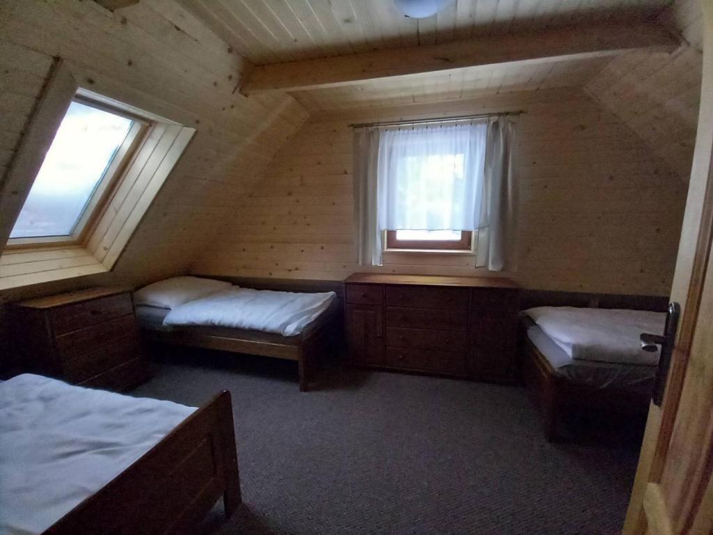 a attic room with two beds and two windows at Drevenica Čertovica in Liptovská Sielnica