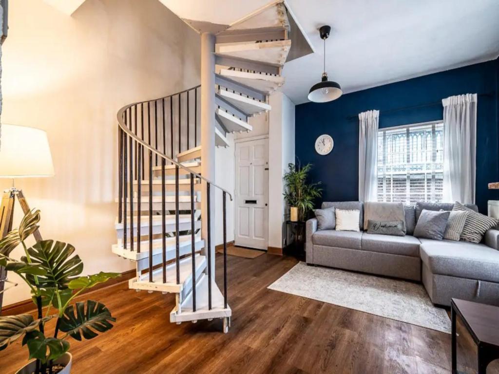 a living room with a couch and a spiral staircase at Pass the Keys Modern central flat with character features in Exeter