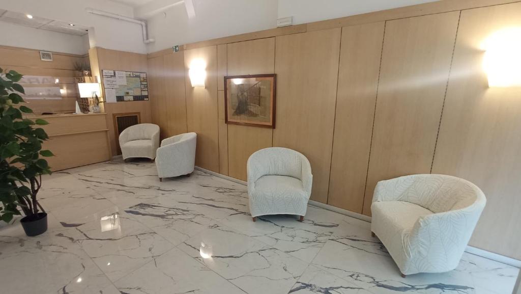 una sala d'attesa con tre sedie e un pavimento in marmo di Hotel Belvedere a Sanremo