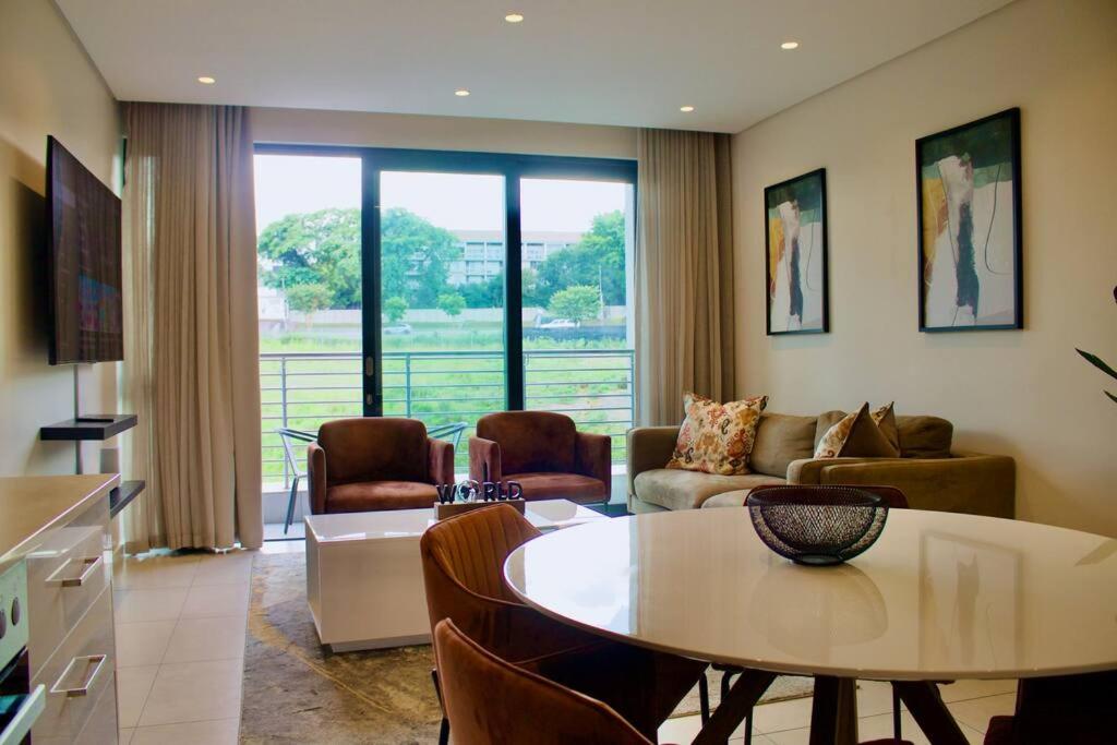 uma sala de estar com uma mesa e um sofá em Outstanding 2BR Sandton with a View em Joanesburgo