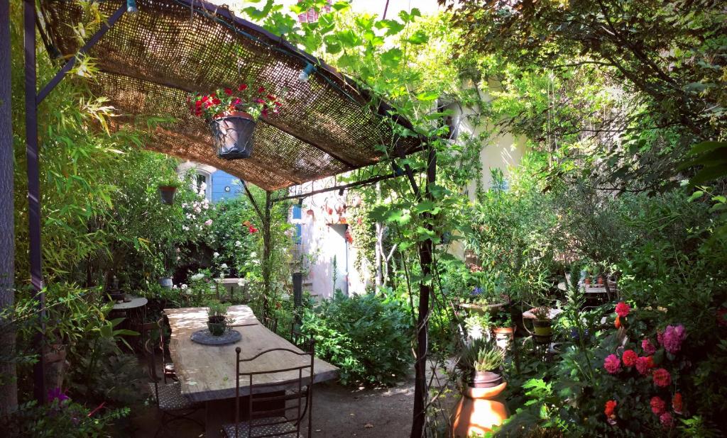 un jardin avec une table, des chaises et des fleurs dans l'établissement Au Puits de la Fontaine, à Tavernes