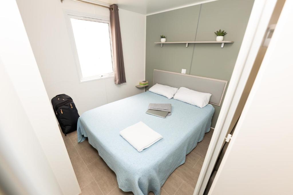 Un dormitorio con una cama con una manta azul y una ventana. en Càmping Bellsol, en Pineda de Mar