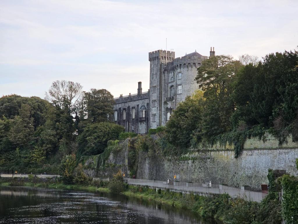 a castle sitting on top of a hill next to a river at Penthouse Apartment in Kilkenny