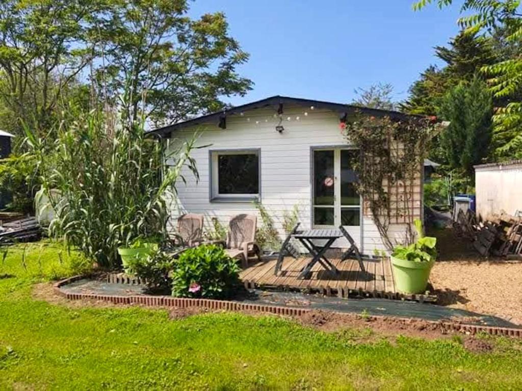 une petite maison blanche avec une table et des chaises dans l'établissement Studio avec jardin clos et wifi a Durtal, à Durtal