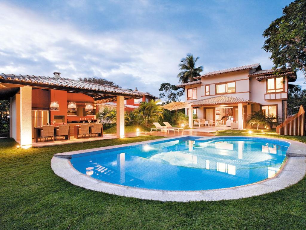 a swimming pool in front of a house at Quintas Private Residence in Costa do Sauipe