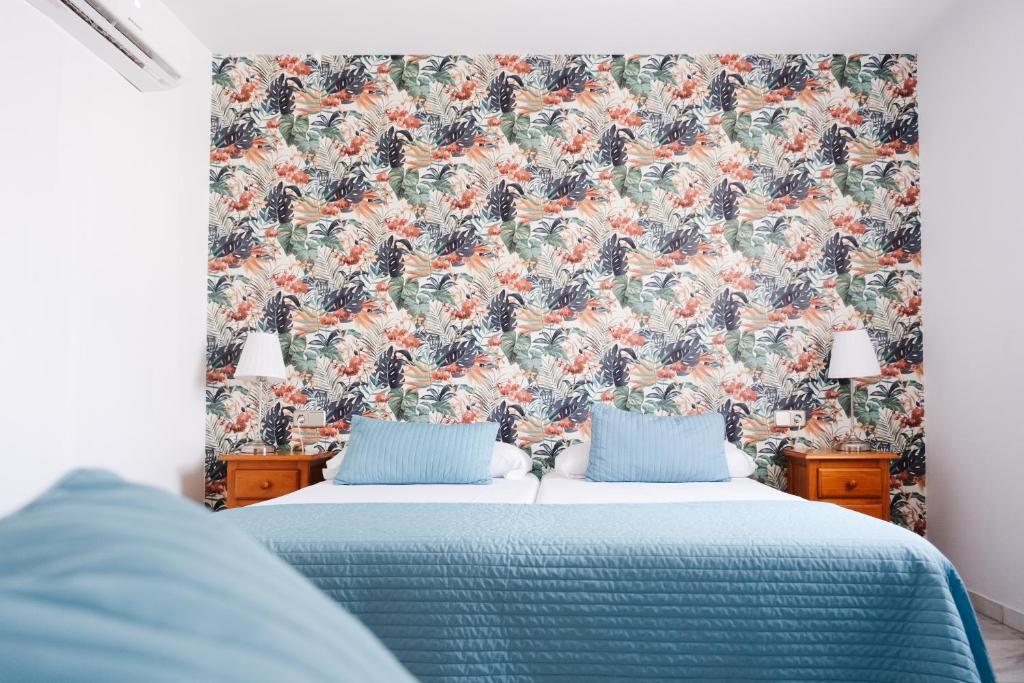 a bedroom with a blue bed with a floral wallpaper at Hotel Isla Menor in Dos Hermanas